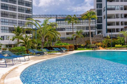 a large swimming pool with blue chairs and buildings at Cozy Apartment 2 Bedrooms Amenities in Acapulco