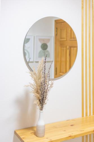 a vase with flowers on a table in front of a mirror at Apartamento Ronda Muralla in Lugo