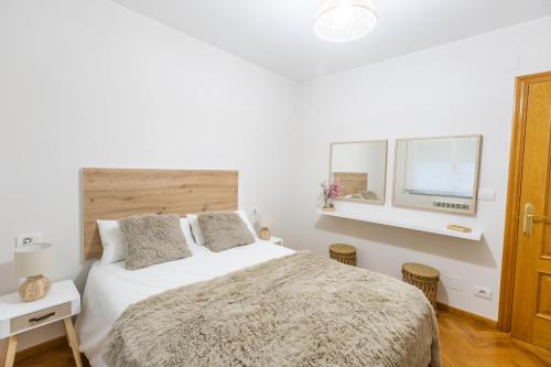 a white bedroom with a bed and two windows at Apartamento Ronda Muralla in Lugo