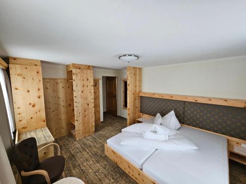 a bedroom with a white bed and a chair at Hotel Koch in Obertauern