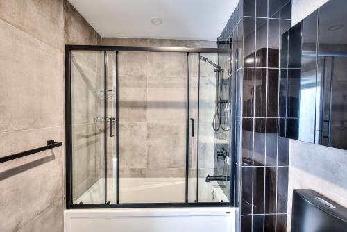 a shower with a glass door in a bathroom at Montreal Restful Nights, Adventure Days await! in Montréal