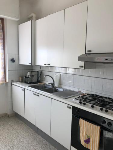 a kitchen with white cabinets and a sink and a stove at Dolce casa con terazza in San Piero a Sieve