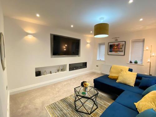 a living room with a blue couch and a tv at House - Sleeps 9 & Private Garden in Leeds