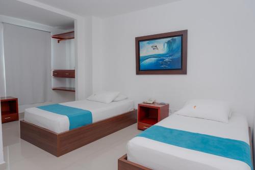 a bedroom with two beds and a picture on the wall at Hotel Aguamarina in Santa Marta