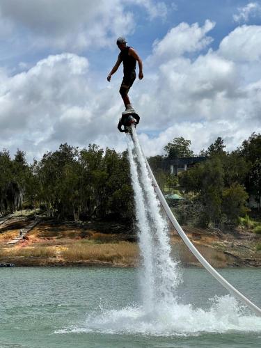 a man is standing on a rope in the water at Cabañas para parejas cerca a Medellín - LUUM By Roots Rentals in Marinilla