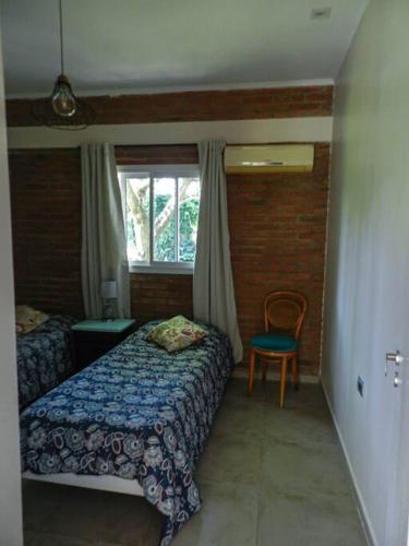 a bedroom with a bed and a chair and a window at Casa Ines in Yerba Buena