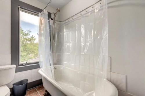 a white bathroom with a tub and a toilet at Oakwoods 1BR Suite in Bankview in Calgary