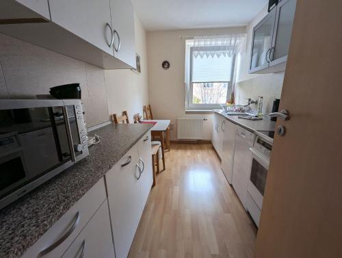a kitchen with white cabinets and a wooden floor at FeWo Lotti - 5 Personen, ruhige Lage, WLAN in Kurort Oberwiesenthal
