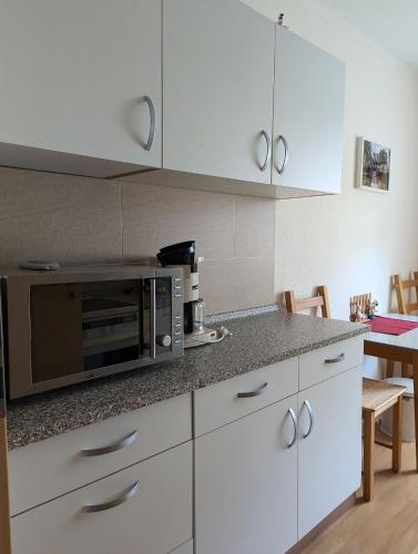 a kitchen with white cabinets and a microwave at FeWo Lotti - 5 Personen, ruhige Lage, WLAN in Kurort Oberwiesenthal