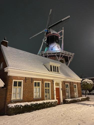 a house with a windmill on top of it at B&B Het Molenhuisje Winschoten - met woonkamer & keuken in Winschoten