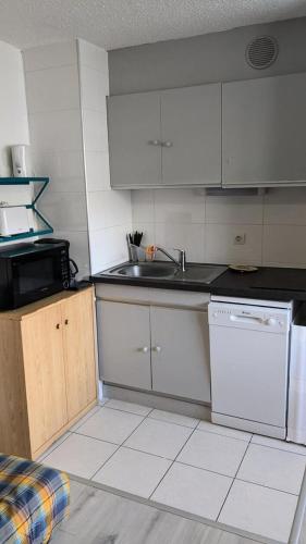 une cuisine avec des armoires blanches, un évier et un lave-vaisselle dans l'établissement Résidence Rond-point-pistes I - Mini studio 19m² 4 pers ROND POINT DES PISTES 1 -N° 122 MAE-7144, à Orcières