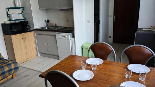 - une table en bois avec des assiettes et des verres dans la cuisine dans l'établissement Résidence Rond-point-pistes I - Mini studio 19m² 4 pers ROND POINT DES PISTES 1 -N° 122 MAE-7144, à Orcières