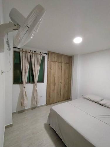 a white bedroom with a bed and two windows at Apto 202, área mtana de Barranquilla in Soledad