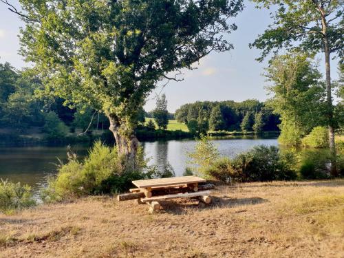 a picnic table sitting next to a lake at Lac privé, forêt, calme absolu dans un gîte tout confort in Saint-Estèphe