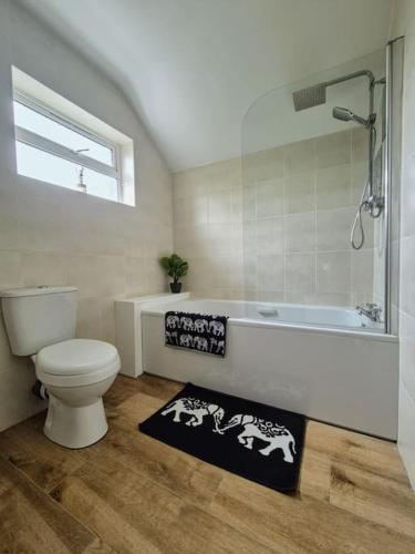 a bathroom with a toilet and a tub and a rug at The Discovery Lodge in Ballykelly