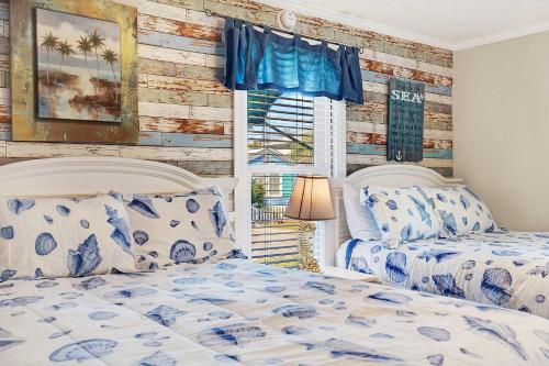 a bedroom with two beds and a wooden wall at Suncatcher Cottage 1508-2nd Avenue A in Tybee Island