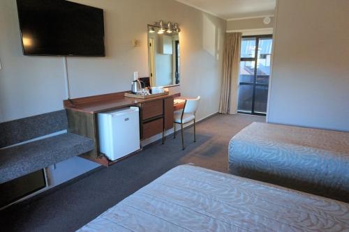 a hotel room with two beds and a desk with a television at The Godley Hotel in Lake Tekapo