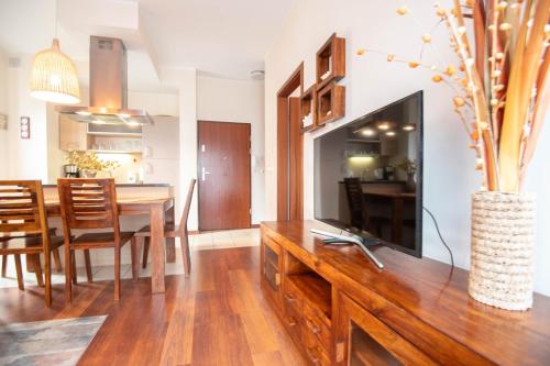 a dining room and living room with a television on a wooden table at Apartamenty Na Wyspie - Baltic Park - Apartamenty z sypialnią i parkingiem - ul Uzdrowiskowa 24-34 in Świnoujście