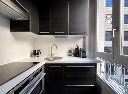 - une cuisine avec des placards noirs et un évier dans l'établissement Champs-Élysées 5 étoiles appartement, à Paris