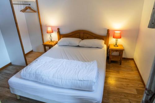 - une chambre avec un lit avec des draps blancs et 2 lampes dans l'établissement Résidence Les Hauts De Preclaux - Appartement avec deux chambres et vue pistes MAE-8191, aux Orres