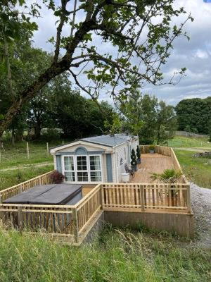a small house with a wooden deck in a field at The Vogue Lodge in Buxton