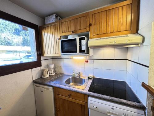 une petite cuisine avec un évier et un micro-ondes dans l'établissement Chalets Jardin Alpin - Chalet Alpin - 8 personnes MAE-9111, à La Salle Les Alpes