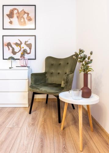 a green chair sitting next to a table with a vase at XOX Comfort Giurgiului in Bucharest