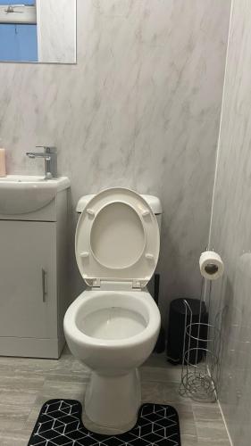 a bathroom with a white toilet and a sink at New Guest House, Individual Ensuite Rooms with Comfortable Double Beds, TV and WiFi in Luton