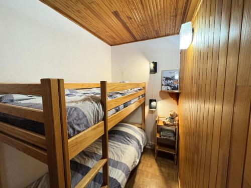 Cette petite chambre dispose de 2 lits superposés et de murs en bois. dans l'établissement Résidence Les Crocus - Studio pour 4 Personnes MAE-9121, à Champcella