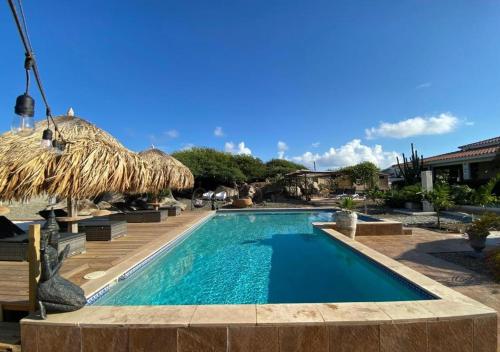 ノールトにあるPura Vida Aruba appartement Papayaの- リゾートのスイミングプール(わら傘付)