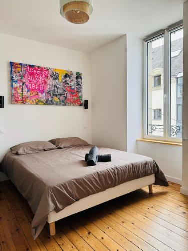 a bed in a bedroom with a painting on the wall at Résidence des Quais - Centre ville - Wifi - Netflix in Quimper