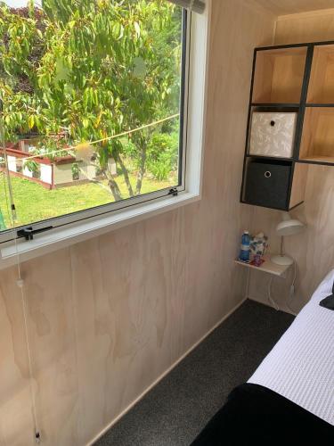 a bedroom with a window with a view of a tree at Herbert Hampden Cottage in Herbert