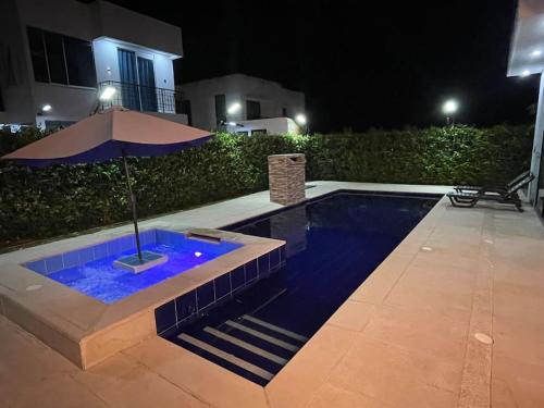a pool with an umbrella next to a house at night at Espectacular Casa de Verano in Carmen de Apicalá