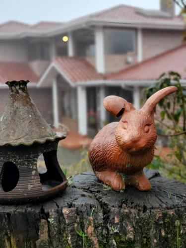 a statue of a toy rabbit sitting on a tree stump at Balcon al Cotopaxi Hosteria in Sangolquí
