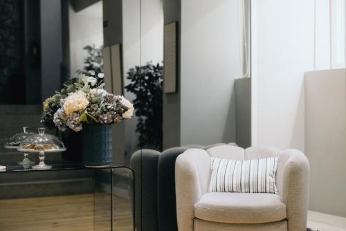 a living room with a chair and a table with a vase of flowers at M'AR De AR Auria in Lisbon