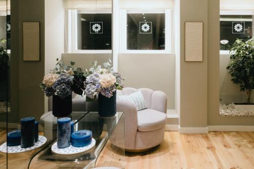 a living room with a chair and a glass table with flowers at M'AR De AR Auria in Lisbon