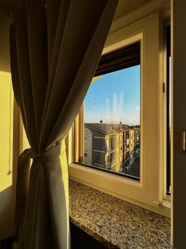 a window with a curtain and a view of a building at G house in Leinì