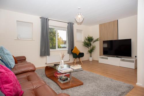 a living room with a couch and a flat screen tv at Cosy townhouse, new build, 5 bedrooms, Sleeps 8, Free Parking in Northfleet