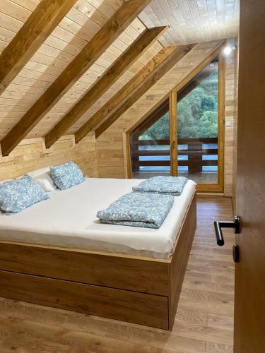 a bed in a room with a large window at Vikendica Ana in Šipovo