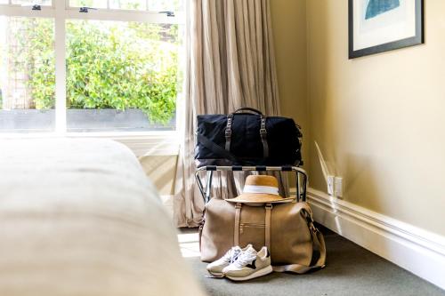 a hat and a bag sitting next to a bed at The White Swan Hotel in Greytown