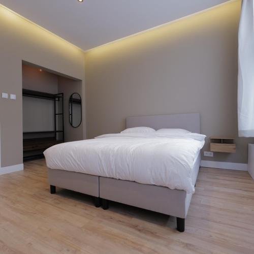 a bedroom with a white bed and a flat screen tv at Living Room Apartments in Rotterdam
