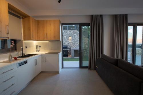 a kitchen with white cabinets and a black couch at Oriens Villas in Palaiokhóri