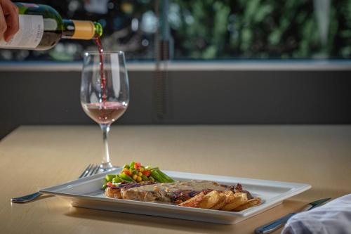 a person pouring a glass of wine over a plate of food at Holiday Inn Puebla La Noria by IHG in Puebla
