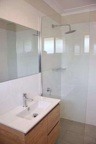 a white bathroom with a sink and a shower at Carrington 6 in South West Rocks