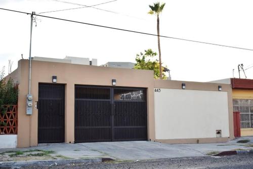 a building with two garage doors and a white billboard at Amplia casa cerca malecón in La Paz