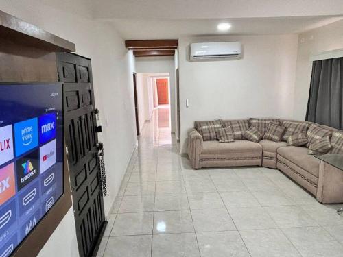 a living room with a couch and a flat screen tv at Amplia casa cerca malecón in La Paz