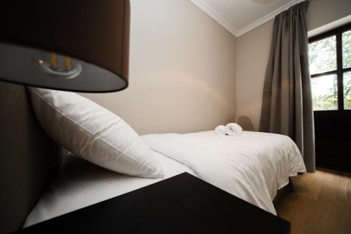 a bedroom with a bed with white sheets and a window at Herzstykke Hotel in Tangstedt
