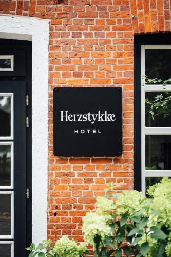 a sign on the side of a brick building at Herzstykke Hotel in Tangstedt