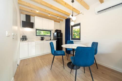 a kitchen and dining room with blue chairs and a table at TOP house with private HOT TUB-near sea, lakes and forest in Kołczewo