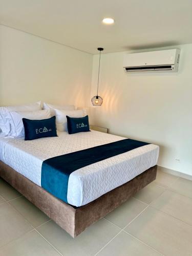 a bedroom with a bed with blue pillows on it at Hotel ECO 44 in Medellín